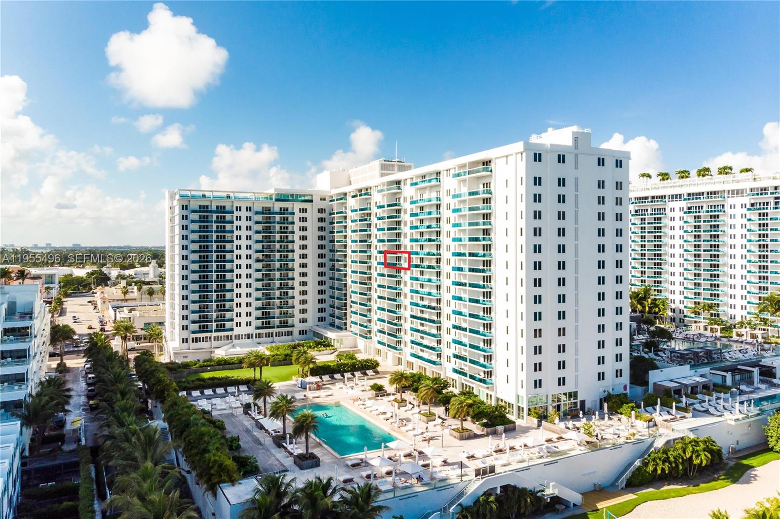 An exterior view of a large white apartment building with a pool and balconies — 2301 Collins Ave # 1006, Miami Beach FL 33139, MIAMI BEACH, FL