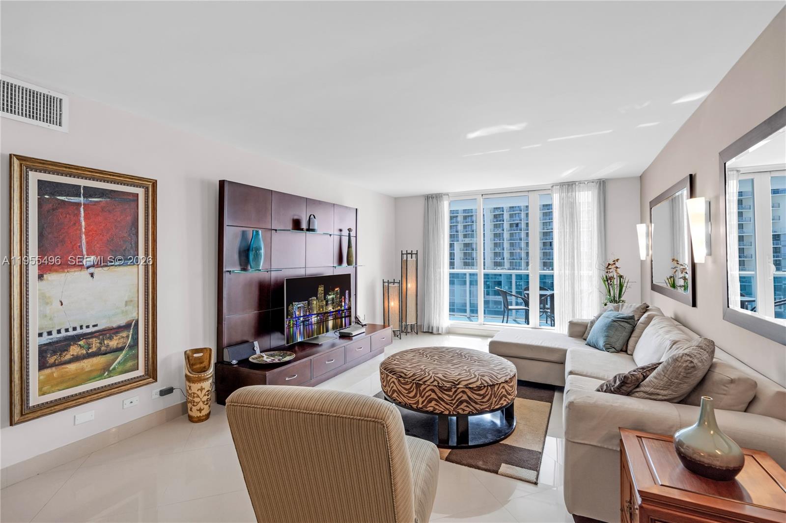 A living room features a sectional sofa, a zebra-print ottoman, and a large media console — 2301 Collins Ave # 1006, Miami Beach FL 33139, MIAMI BEACH, FL