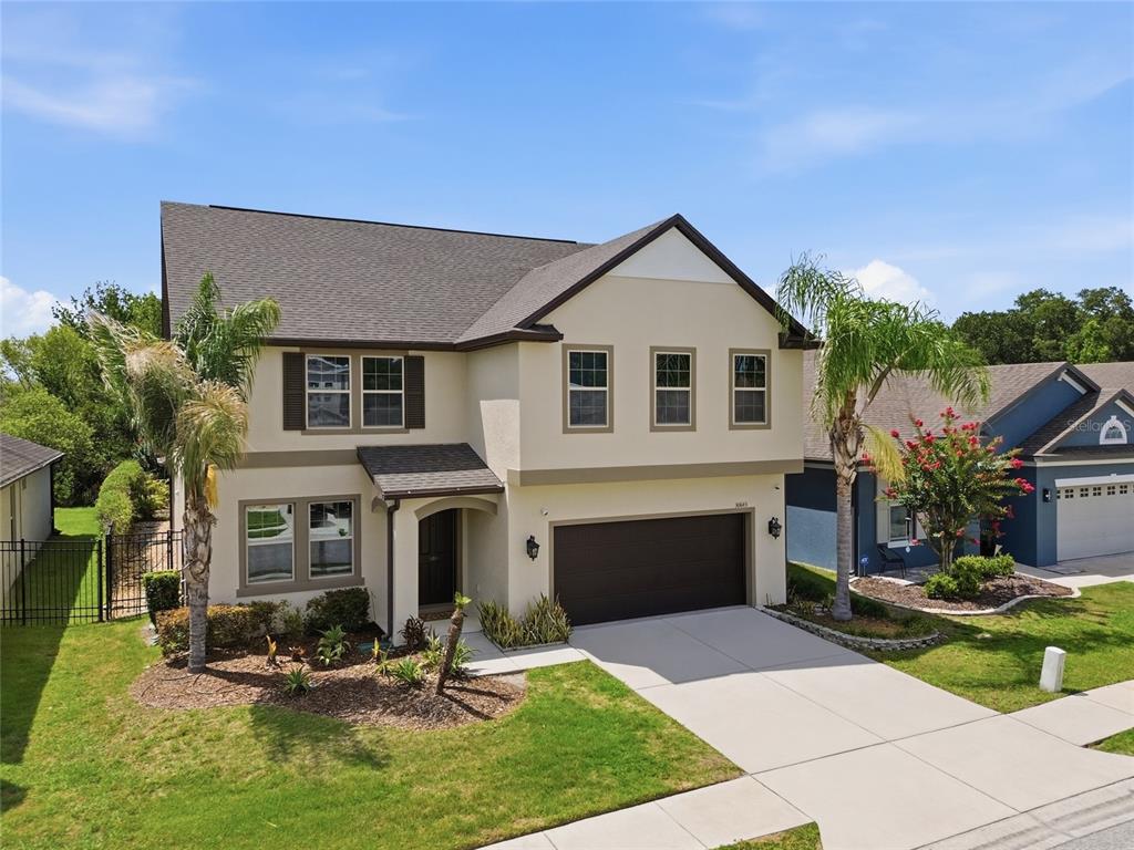 A two-story suburban house with a beige stucco exterior, dark roof, and two-car garage — 30643 WALKER CUP PLACE, WESLEY CHAPEL, FL