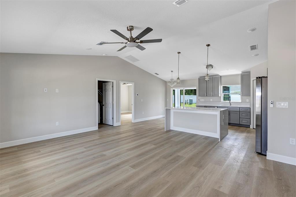 An open-concept living area features light wood flooring, a vaulted ceiling, and a modern kitchen — 10431 SW 140TH AVENUE, DUNNELLON, FL