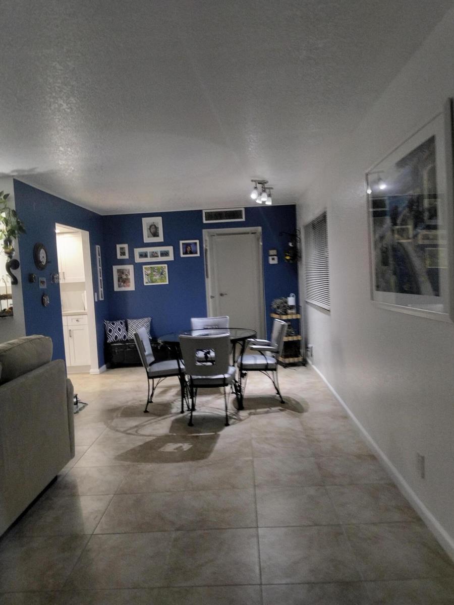 A dining area features a glass table, four chairs, and a blue accent wall — 399 Brittany # L, Delray Beach FL 33446, DELRAY BEACH, FL