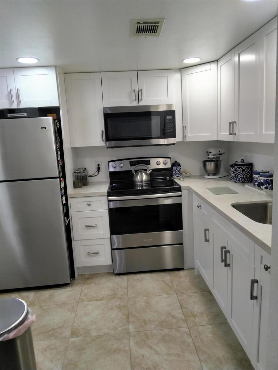 A kitchen with white cabinets, stainless steel appliances, and light-colored tile flooring — 399 Brittany # L, Delray Beach FL 33446, DELRAY BEACH, FL