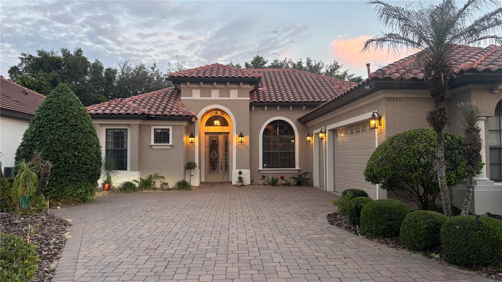 A single-story stucco house with a tile roof and a paved driveway at dusk — 26345 SAN GABRIEL, HOWEY IN THE HILLS, FL
