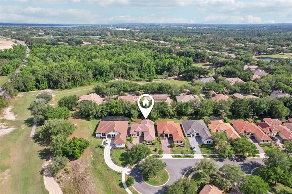 An aerial view shows a suburban house with a pool cage in a residential neighborhood — 26345 SAN GABRIEL, HOWEY IN THE HILLS, FL