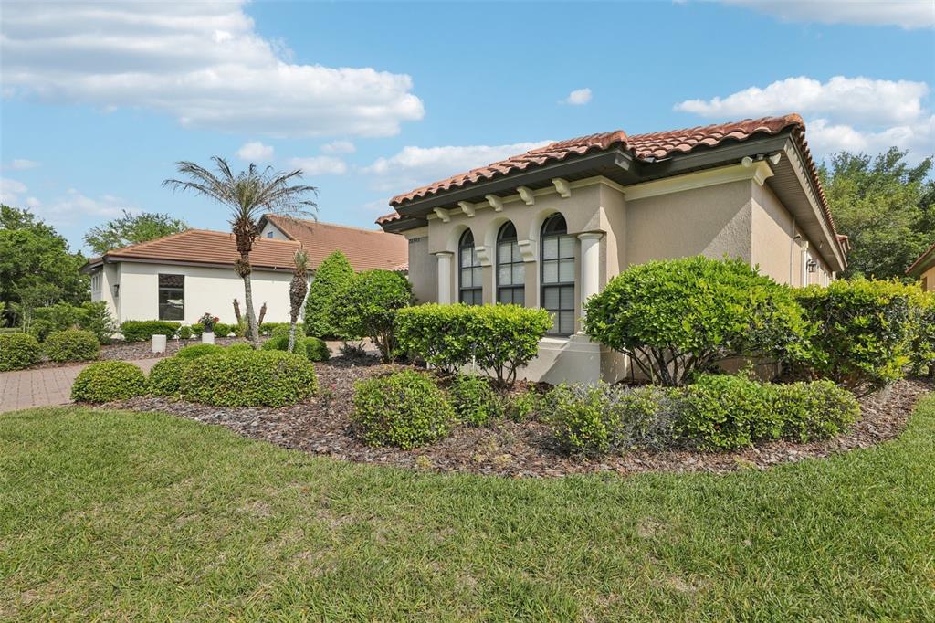 A single-story stucco house with a tile roof and landscaped front yard under a blue sky — 26345 SAN GABRIEL, HOWEY IN THE HILLS, FL