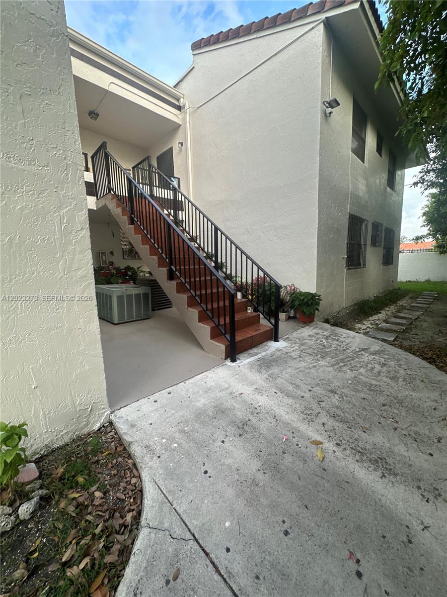 An exterior view shows a concrete staircase with black railings leading to an upper level — 10893 NW 7th St # 27, Miami FL 33172, MIAMI, FL