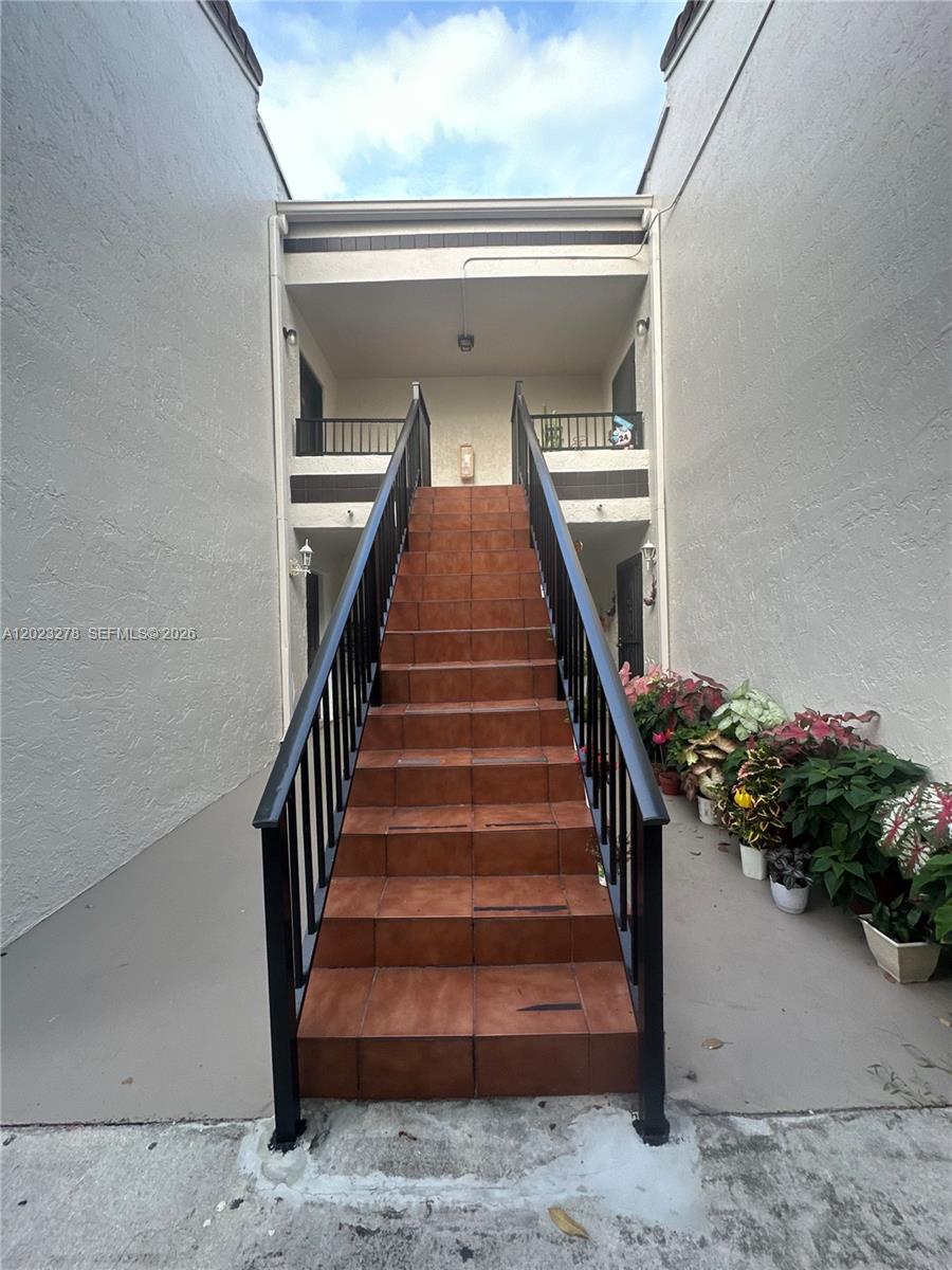 An outdoor staircase with brown tile steps leads to a two-story apartment building entrance — 10893 NW 7th St # 27, Miami FL 33172, MIAMI, FL