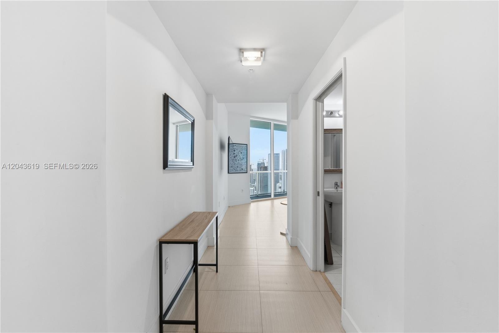 A hallway with light tile flooring leads to a room with floor-to-ceiling windows — 1900 N Bayshore Dr, Miami FL 33132, MIAMI, FL