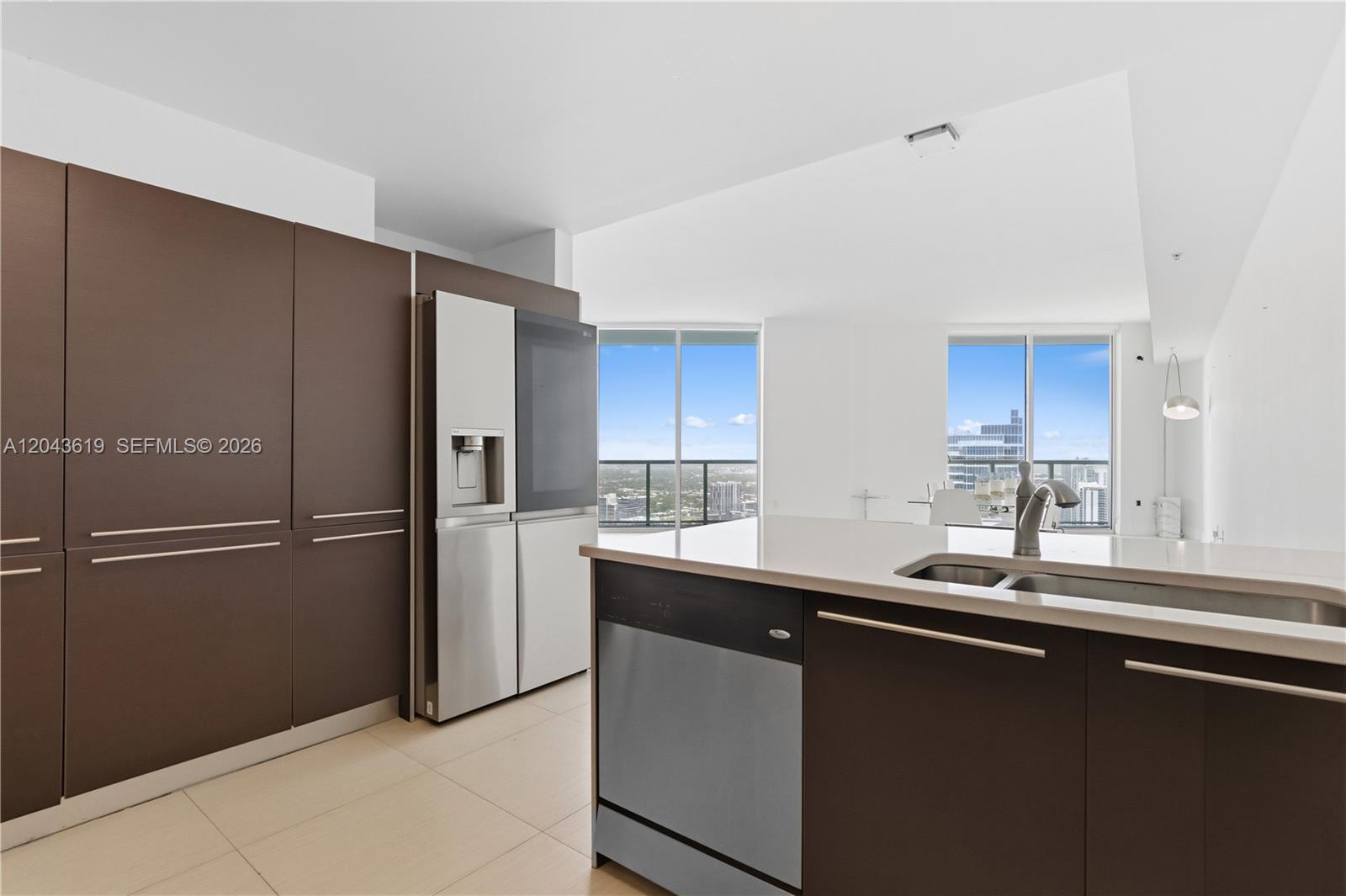 A modern kitchen features dark brown cabinetry, stainless steel appliances, and a white island countertop — 1900 N Bayshore Dr, Miami FL 33132, MIAMI, FL