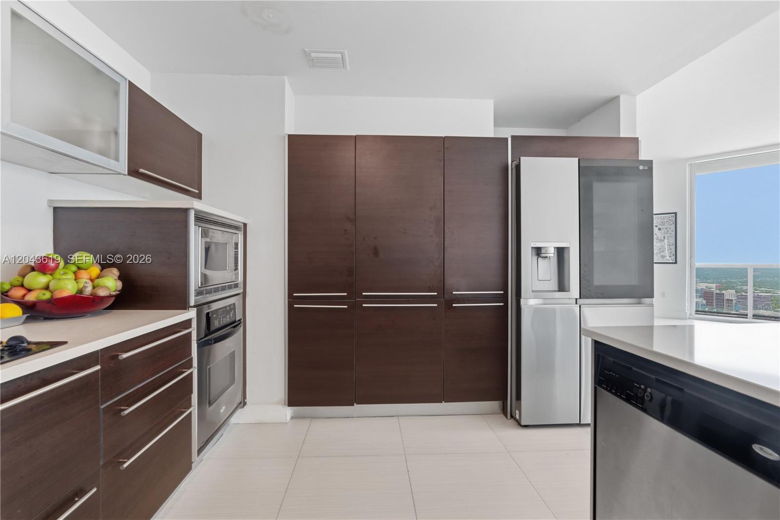 A modern kitchen features dark wood cabinetry, stainless steel appliances, and a view of buildings — 1900 N Bayshore Dr, Miami FL 33132, MIAMI, FL