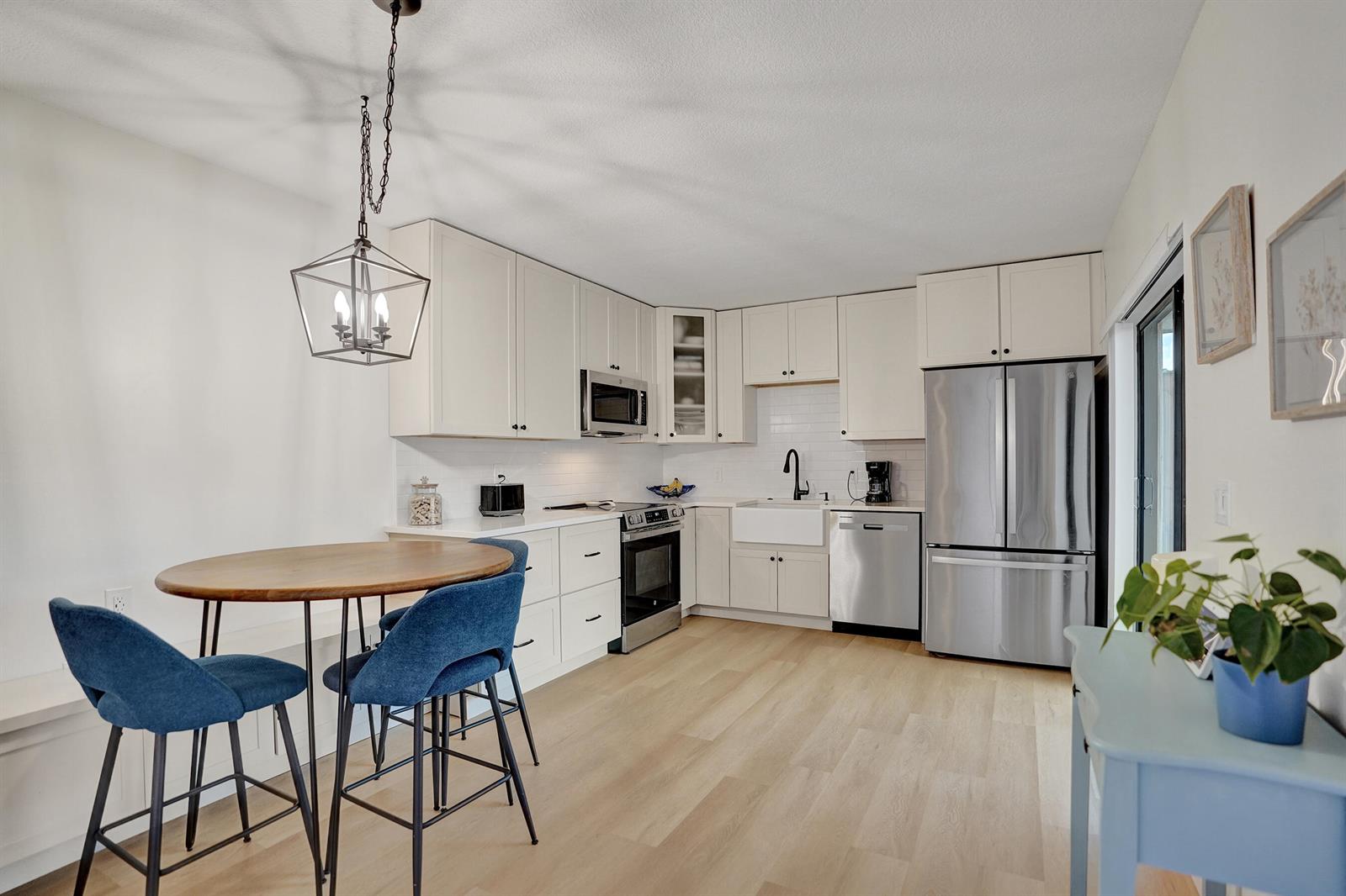 A kitchen with white cabinets, stainless steel appliances, a farmhouse sink, and a dining area — 1126 11th Lane, Palm Beach Gardens FL 33418, PALM BEACH GARDENS, FL