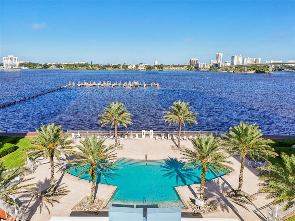 An elevated view of a swimming pool with palm trees overlooking a large body of water — 241 RIVERSIDE DRIVE UNIT 305, DAYTONA BEACH, FL