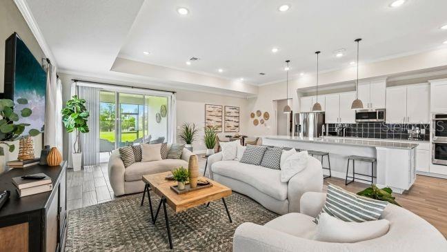 An open-concept living room and kitchen featuring white cabinetry, a large island, and sliding doors — 9 LAURELCHERRY COURT, HOMOSASSA, FL