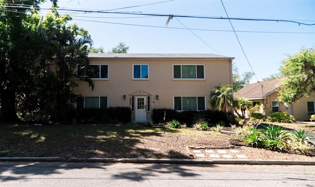 A two-story tan apartment building with a central white front door and surrounding landscaping — 400 20TH STREET E UNIT 1-6, BRADENTON, FL