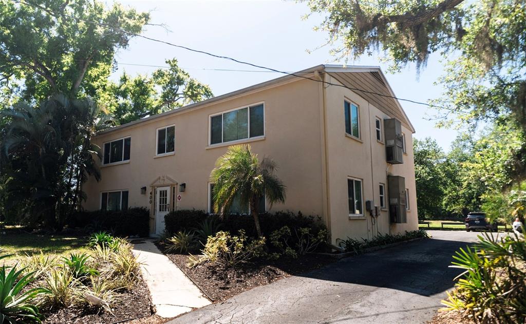 A two-story, tan-colored apartment building features a paved driveway and a landscaped front walkway — 400 20TH STREET E UNIT 1-6, BRADENTON, FL