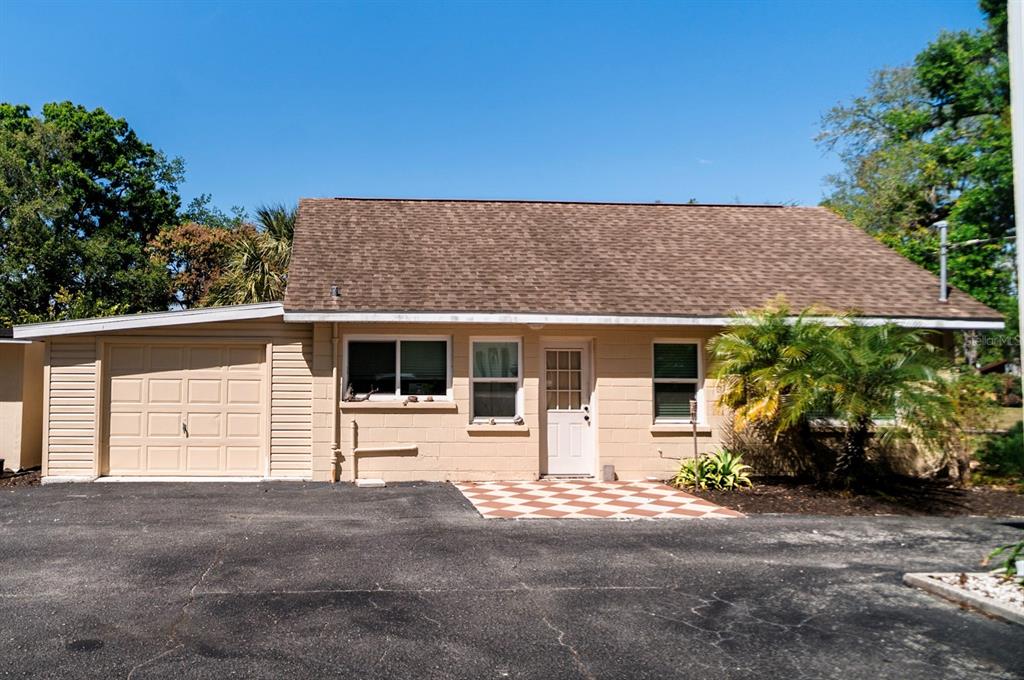 A single-story house with a tan block exterior, a brown shingled roof, and an attached garage — 400 20TH STREET E UNIT 1-6, BRADENTON, FL