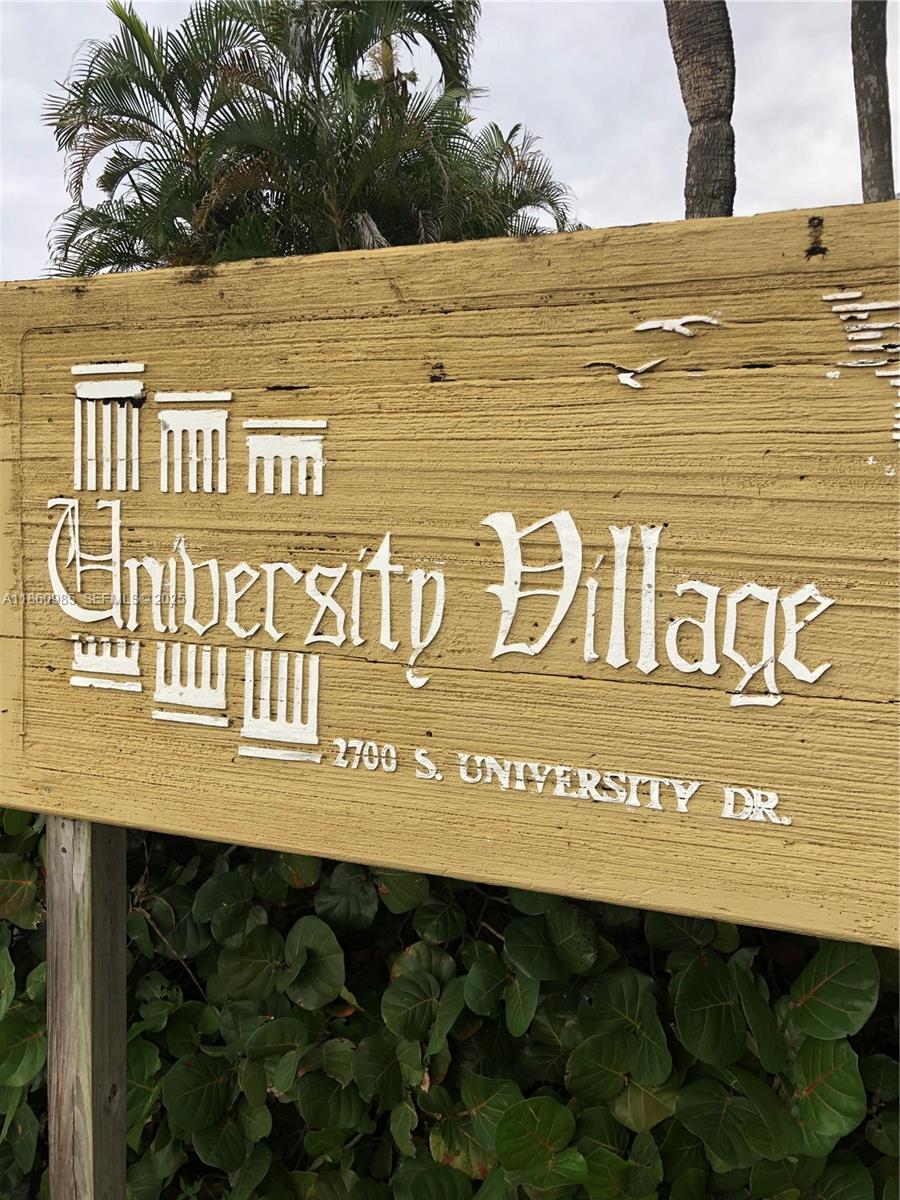 A wooden sign for University Village stands outdoors in front of green foliage — 2800 S University Dr # 2A, Davie FL 33328, DAVIE, FL