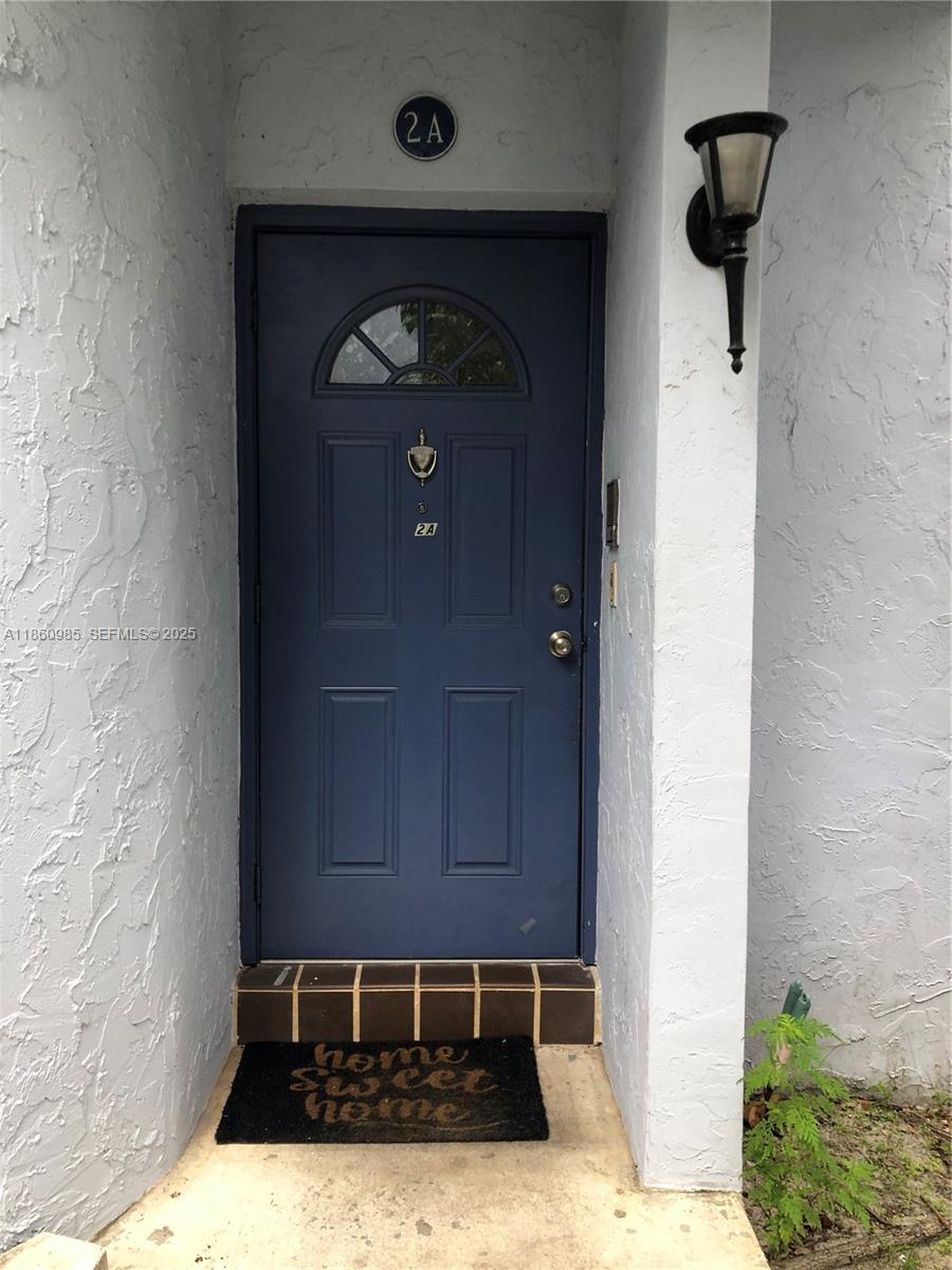 A blue front door with a small window and a welcome mat sits outside — 2800 S University Dr # 2A, Davie FL 33328, DAVIE, FL