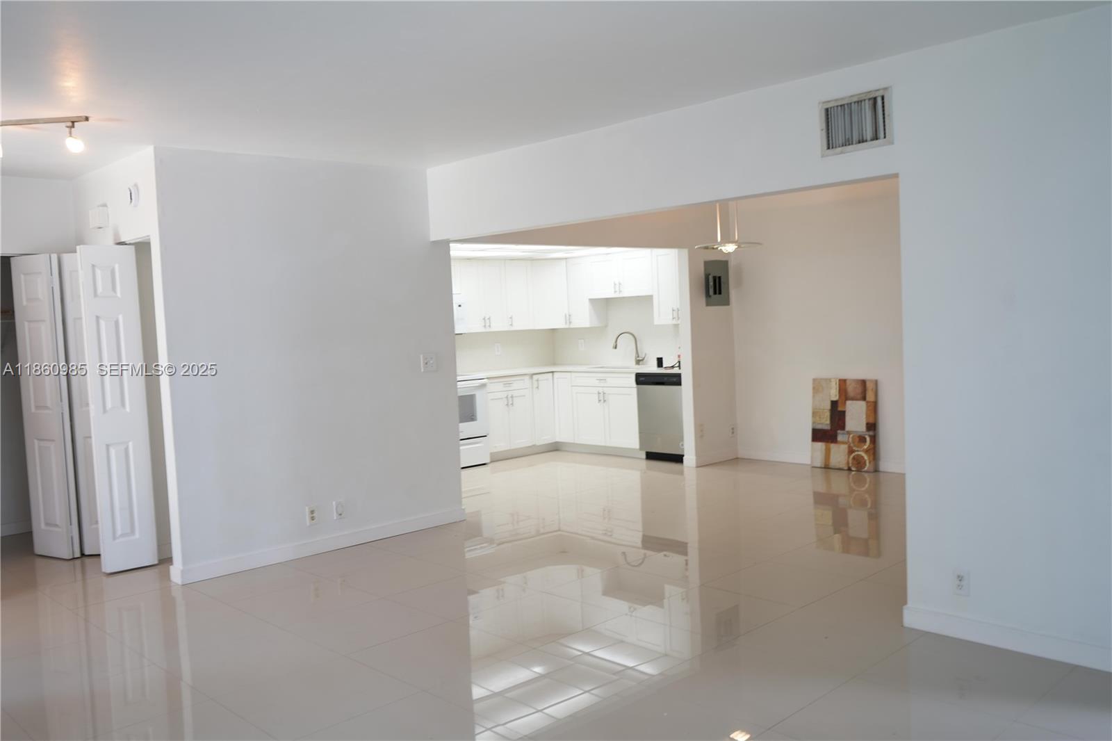 A bright, open-concept kitchen features white cabinetry, stainless steel appliances, and glossy tile flooring — 2800 S University Dr # 2A, Davie FL 33328, DAVIE, FL