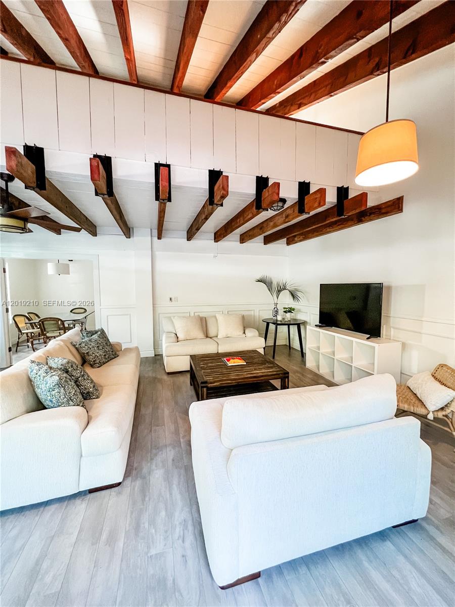 A living room features white sofas, a wooden coffee table, and exposed ceiling beams — 320 W 55th St, Miami Beach FL 33140, MIAMI BEACH, FL
