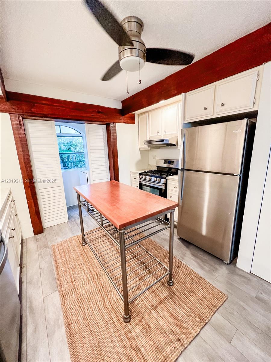A kitchen features a wooden island, stainless steel appliances, and exposed dark wood ceiling beams — 320 W 55th St, Miami Beach FL 33140, MIAMI BEACH, FL