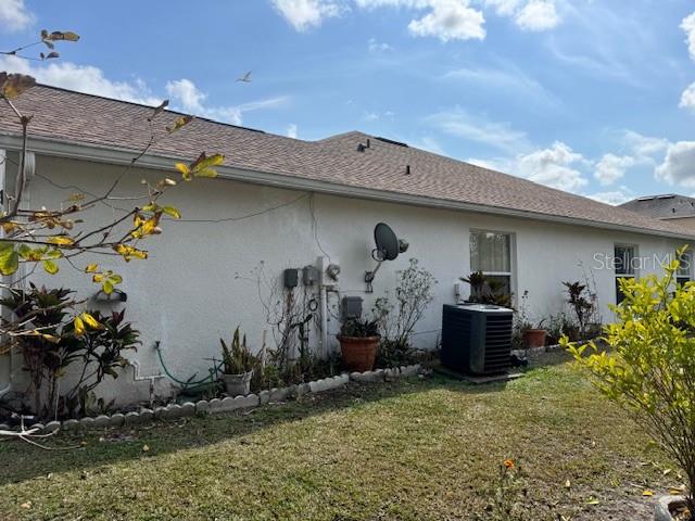 The exterior of a stucco house features a satellite dish, an air conditioning unit, and landscaping — 813 HALIFAX DRIVE, KISSIMMEE, FL