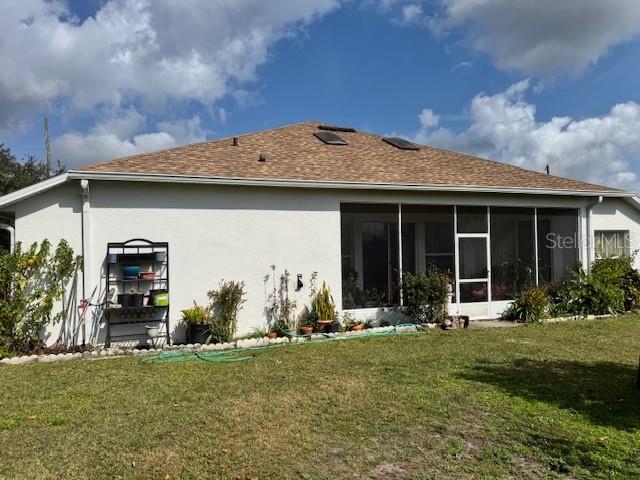 The rear exterior of a house features a screened-in porch and a metal plant stand — 813 HALIFAX DRIVE, KISSIMMEE, FL