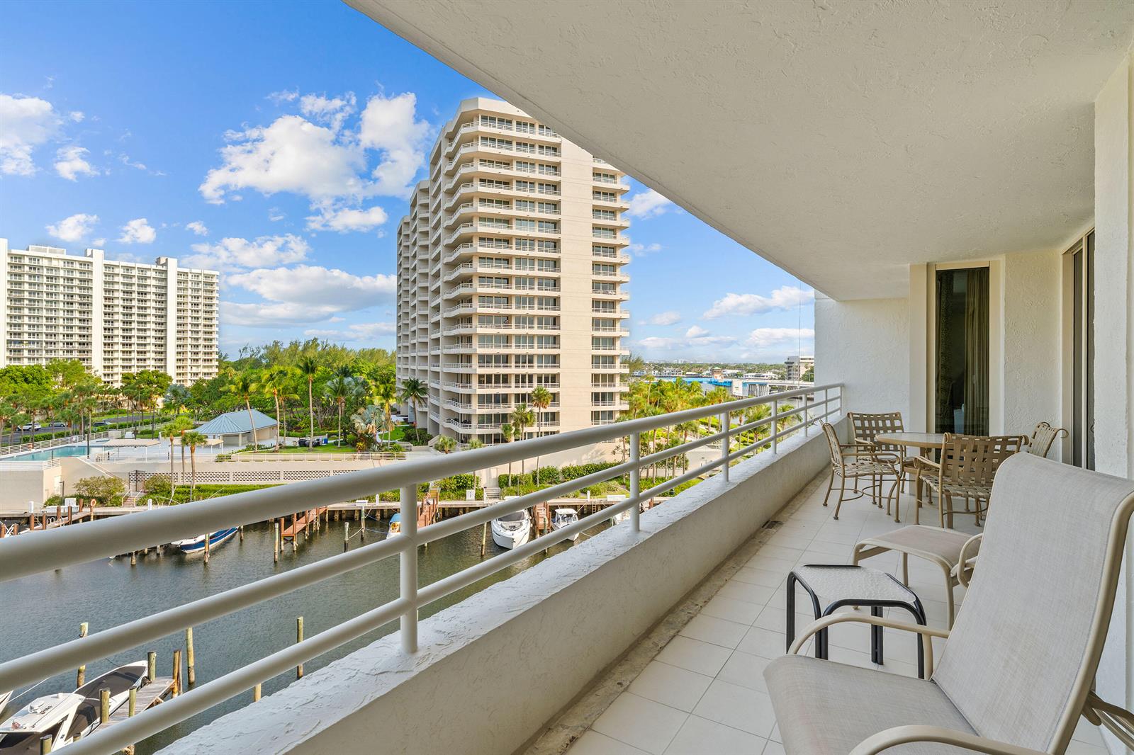 A balcony with outdoor furniture overlooks a canal, boat slips, and high-rise apartment buildings — 4201 N Ocean Boulevard # 508, Boca Raton FL 33431, BOCA RATON, FL