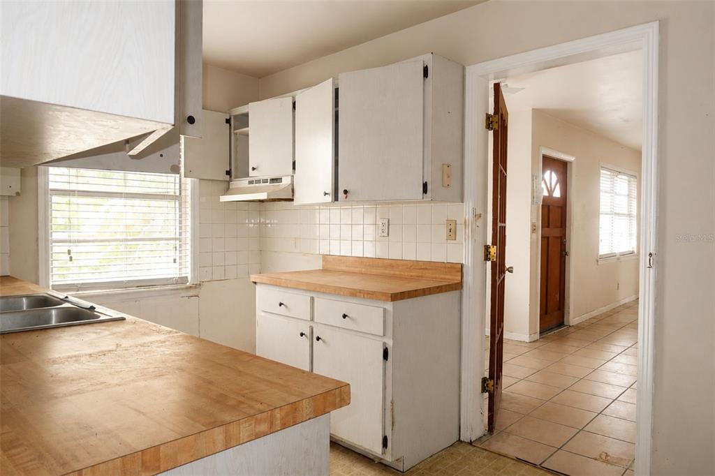 A kitchen with white cabinets, wood countertops, and a doorway leading to a tiled hallway — 1302 28TH STREET W, BRADENTON, FL