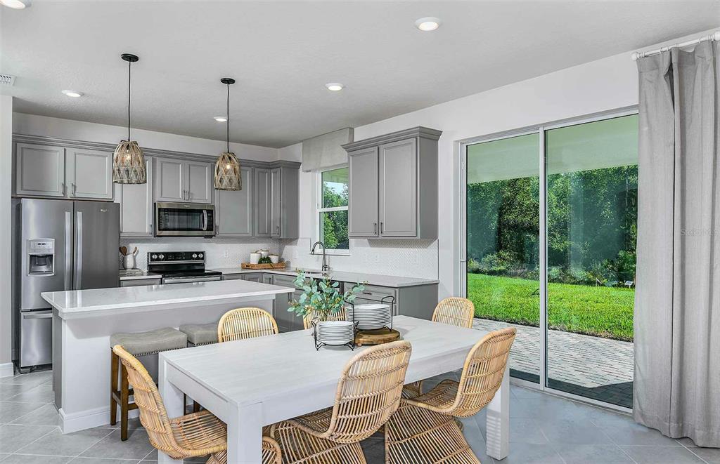 A kitchen and dining area with gray cabinets, white countertops, and a sliding glass door — 11119 SYCAMORE GLEN LOOP, THONOTOSASSA, FL