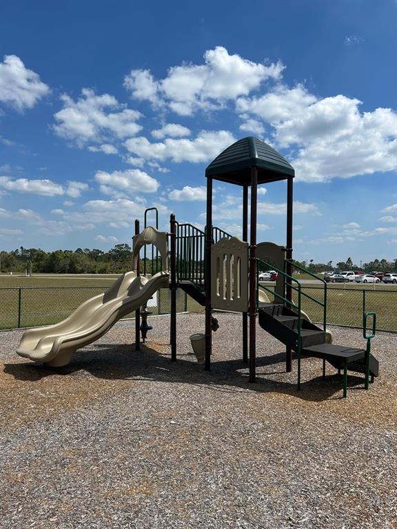 A playground structure with a slide and stairs sits on a wood-chipped surface outdoors — 1020 ALTHEA DRIVE, INDIAN LAKE ESTATES, FL