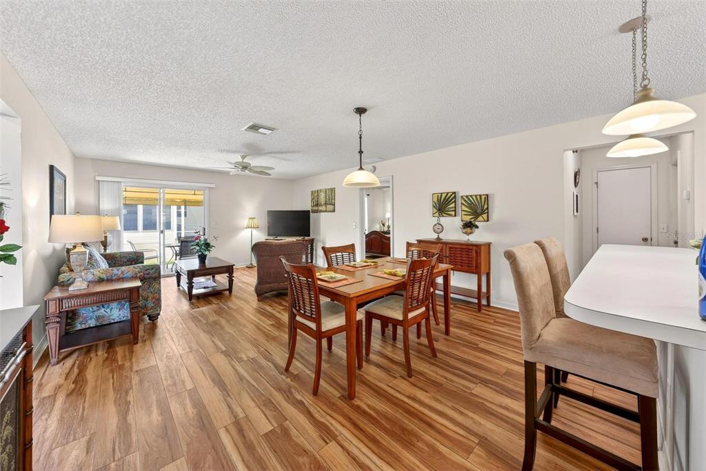 An open-concept living and dining area features wood-look flooring and a breakfast bar — 1088 GENNESSE LANE, THE VILLAGES, FL
