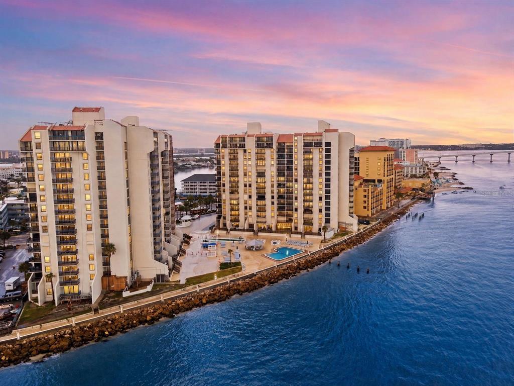 An aerial view of two high-rise waterfront condominium buildings with a pool at sunset — 450 S GULFVIEW BOULEVARD UNIT 705, CLEARWATER BEACH, FL