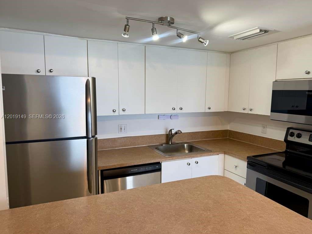 A kitchen features white cabinets, stainless steel appliances, and tan laminate countertops — 770 Claughton Island Dr # 706, Miami FL 33131, MIAMI, FL