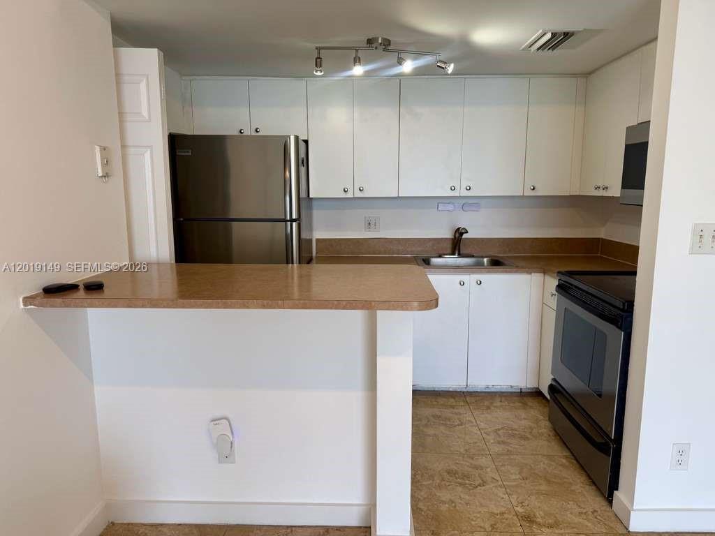 A kitchen features white cabinets, stainless steel appliances, a tan countertop, and tile flooring — 770 Claughton Island Dr # 706, Miami FL 33131, MIAMI, FL