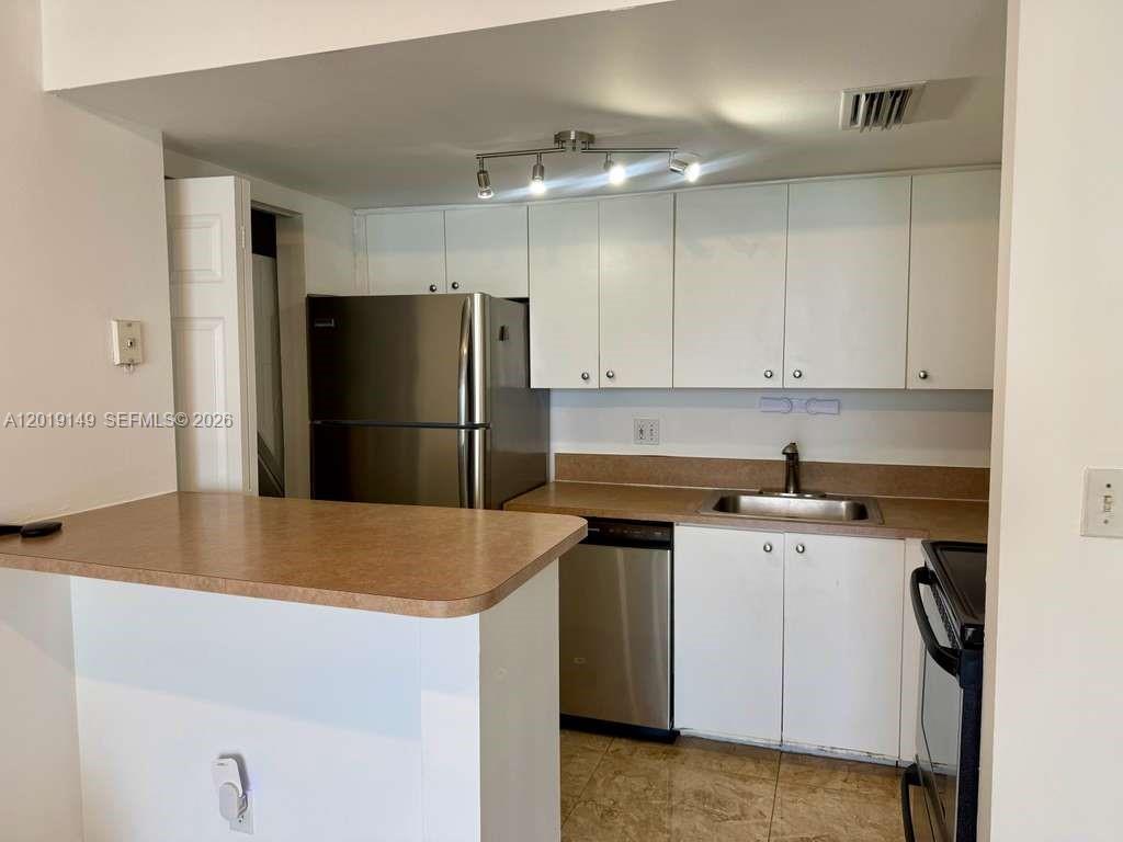 A kitchen features white cabinets, stainless steel appliances, and a breakfast bar with laminate countertops — 770 Claughton Island Dr # 706, Miami FL 33131, MIAMI, FL