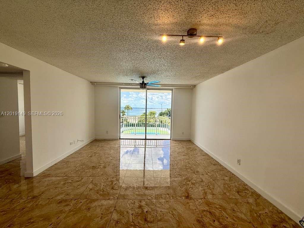 An empty room features tan marble-look tile flooring, a ceiling fan, and a sliding glass door — 770 Claughton Island Dr # 706, Miami FL 33131, MIAMI, FL
