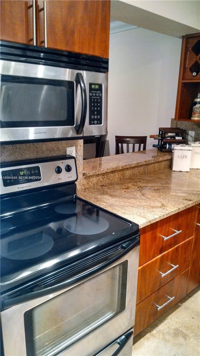 A kitchen features stainless steel appliances, wood cabinets, and granite countertops — 126 SW 17th Rd # 301, Miami FL 33129, MIAMI, FL