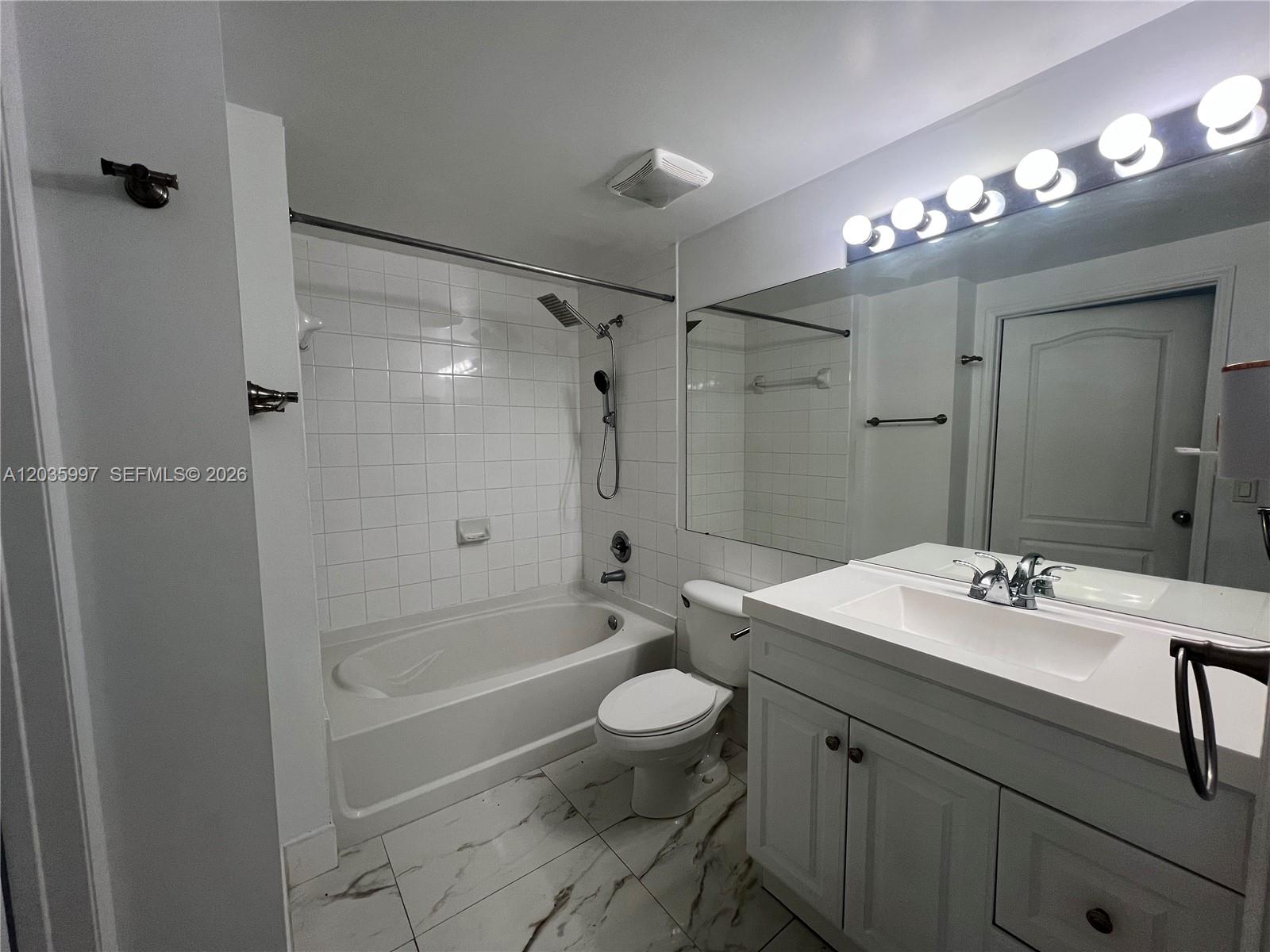 A bathroom features a white vanity, a toilet, and a shower-tub combination with white tiles — 5085 NW 7th St # 711, Miami FL 33126, MIAMI, FL