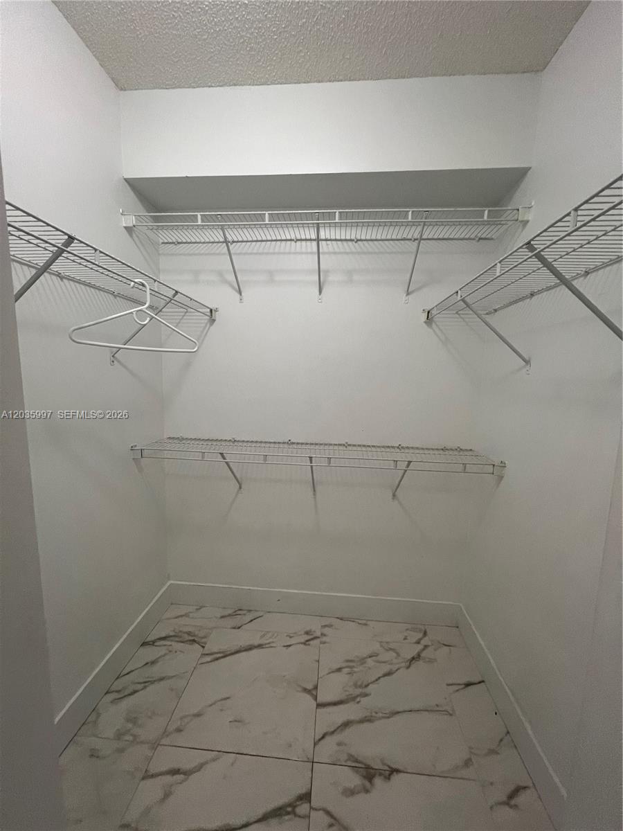 A walk-in closet features white walls, wire shelving, and light-colored marble-patterned floor tiles — 5085 NW 7th St # 711, Miami FL 33126, MIAMI, FL