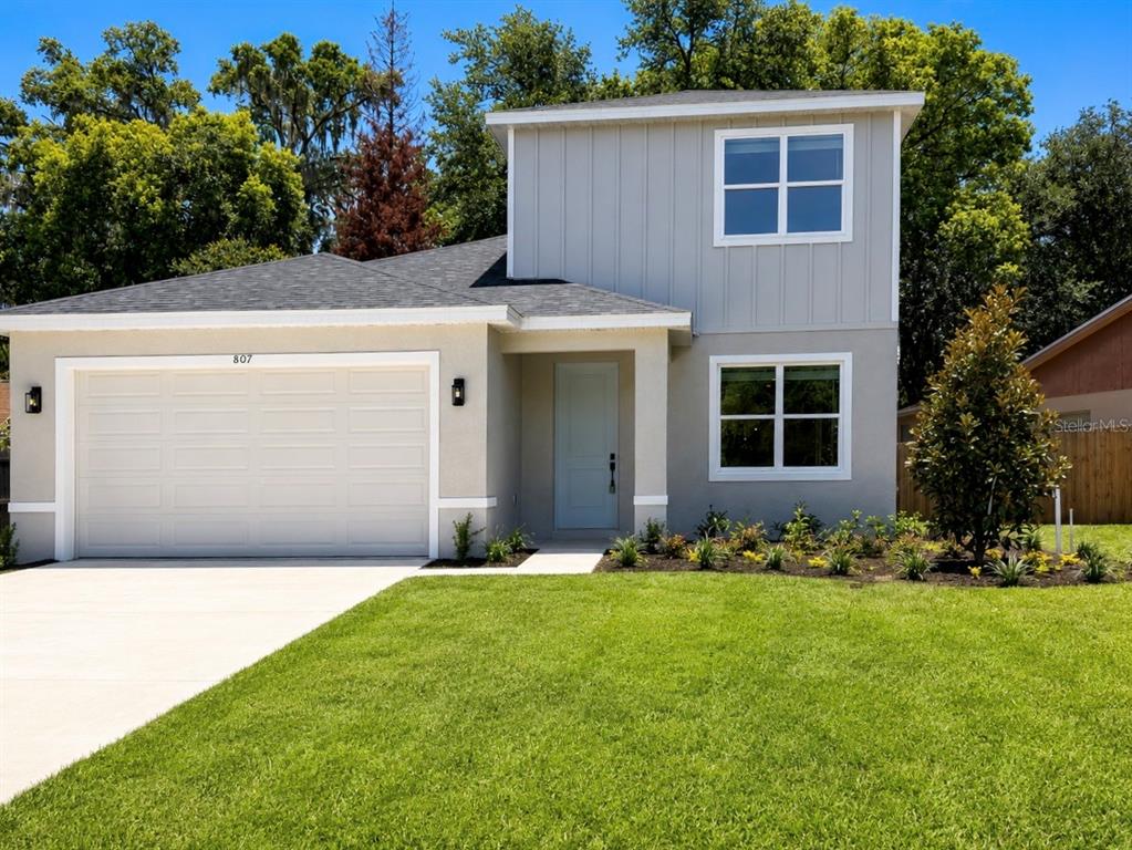 A two-story house with a light gray exterior, a white garage door, and a front lawn — 807 SANTA BARBARA DRIVE, SANFORD, FL