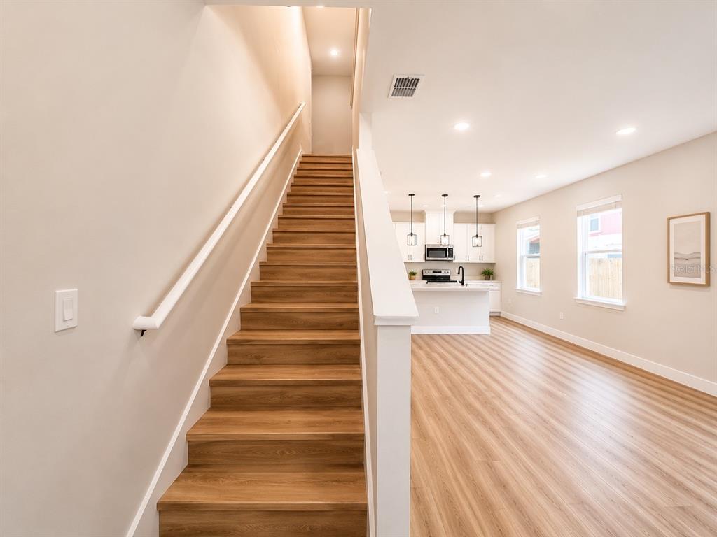 A bright, open-concept kitchen and living area features light wood flooring and white cabinetry — 807 SANTA BARBARA DRIVE, SANFORD, FL