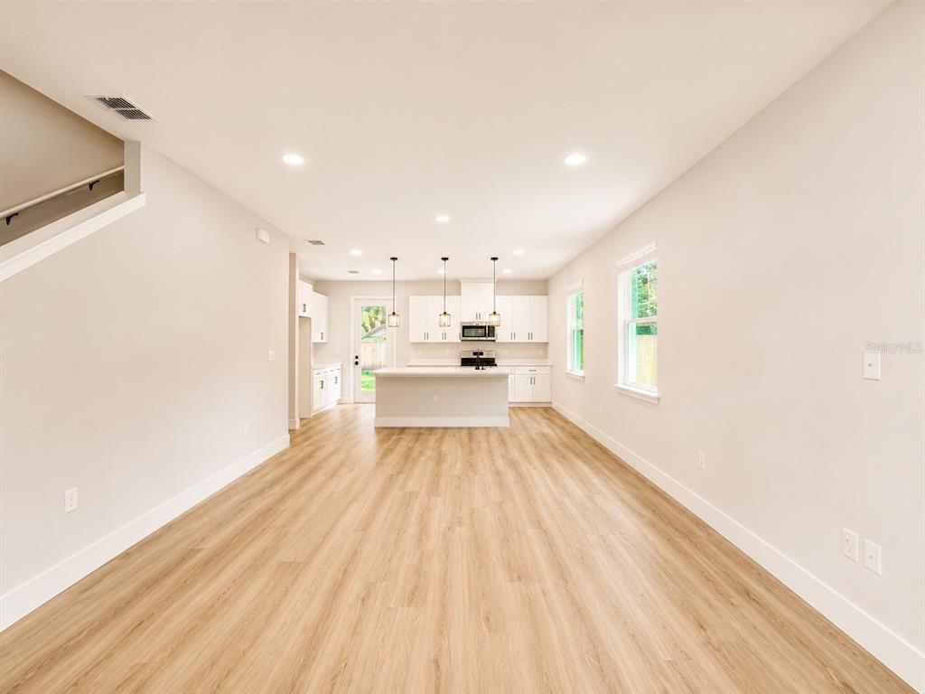 This is a rendering of an open-concept living room and kitchen with light wood flooring — 807 SANTA BARBARA DRIVE, SANFORD, FL