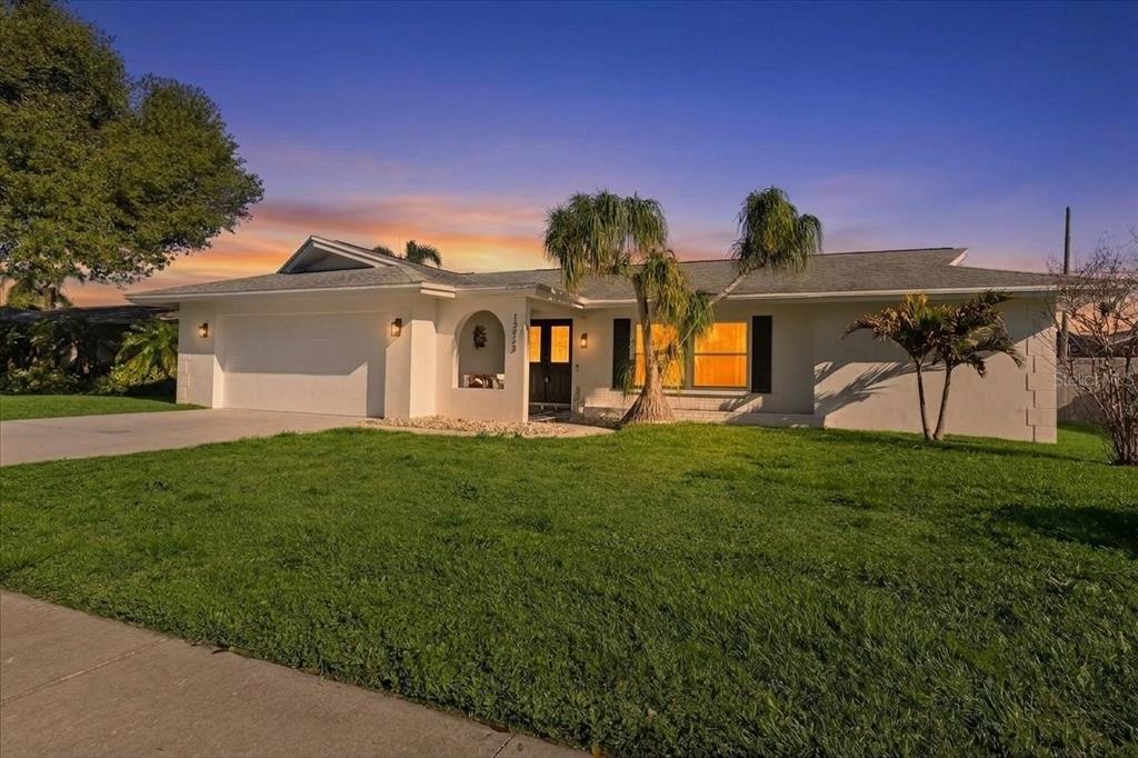 A single-story white house with a two-car garage and palm trees in the front yard — 13923 BREWSTER DRIVE, LARGO, FL