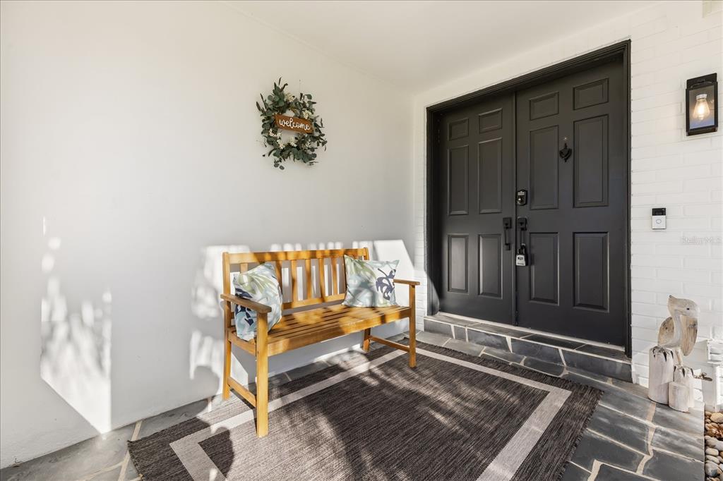 A wooden bench sits on a rug in front of a black double front door — 13923 BREWSTER DRIVE, LARGO, FL
