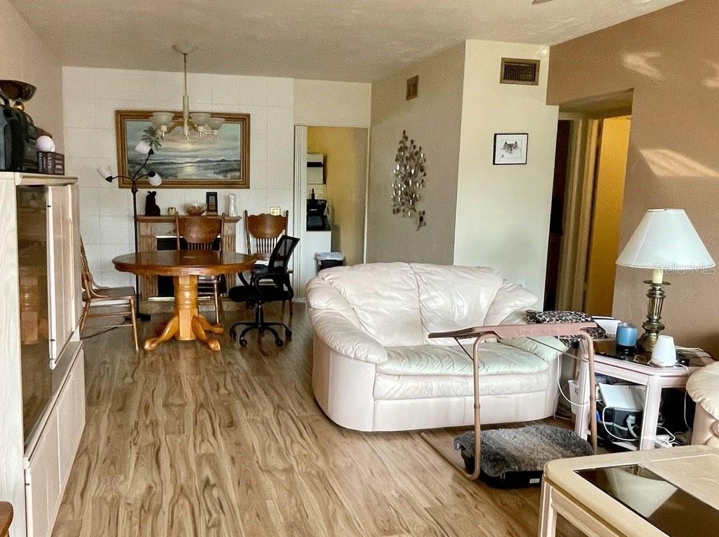 A living and dining area featuring light wood-look flooring, a white sofa, and a table — 4060 55TH STREET N UNIT 1209, KENNETH CITY, FL