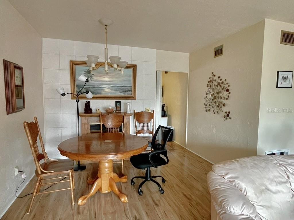 A dining area features a round wooden table, mismatched chairs, a fireplace, and tiled walls — 4060 55TH STREET N UNIT 1209, KENNETH CITY, FL