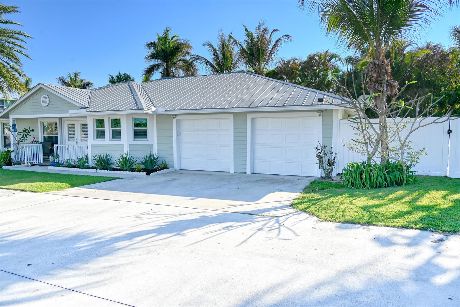 A light green single-story house features a metal roof, two garage doors, and palm trees — 126 Faith Way, Jupiter FL 33458, JUPITER, FL