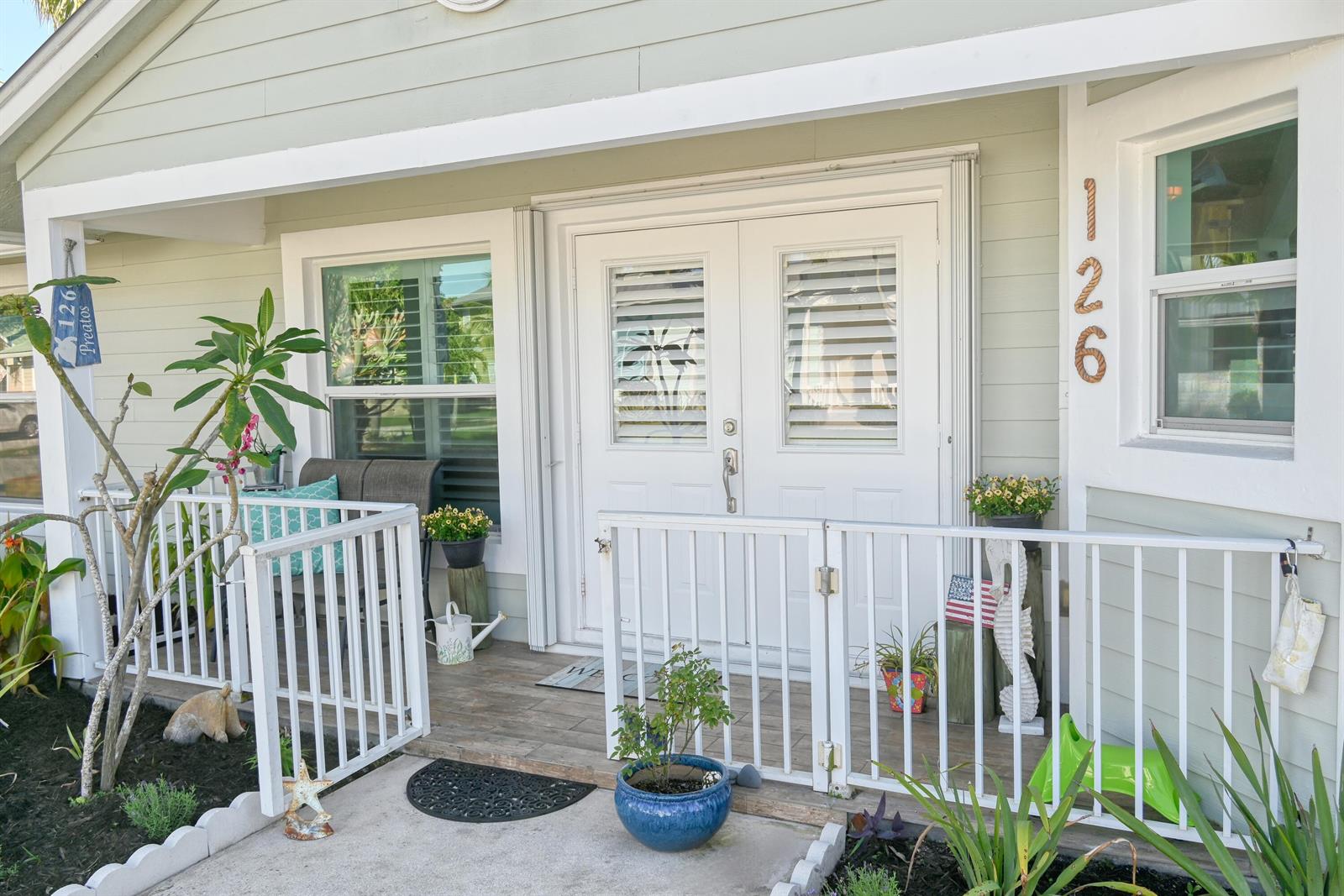 A light green house exterior features a white double door, porch railing, and house numbers — 126 Faith Way, Jupiter FL 33458, JUPITER, FL
