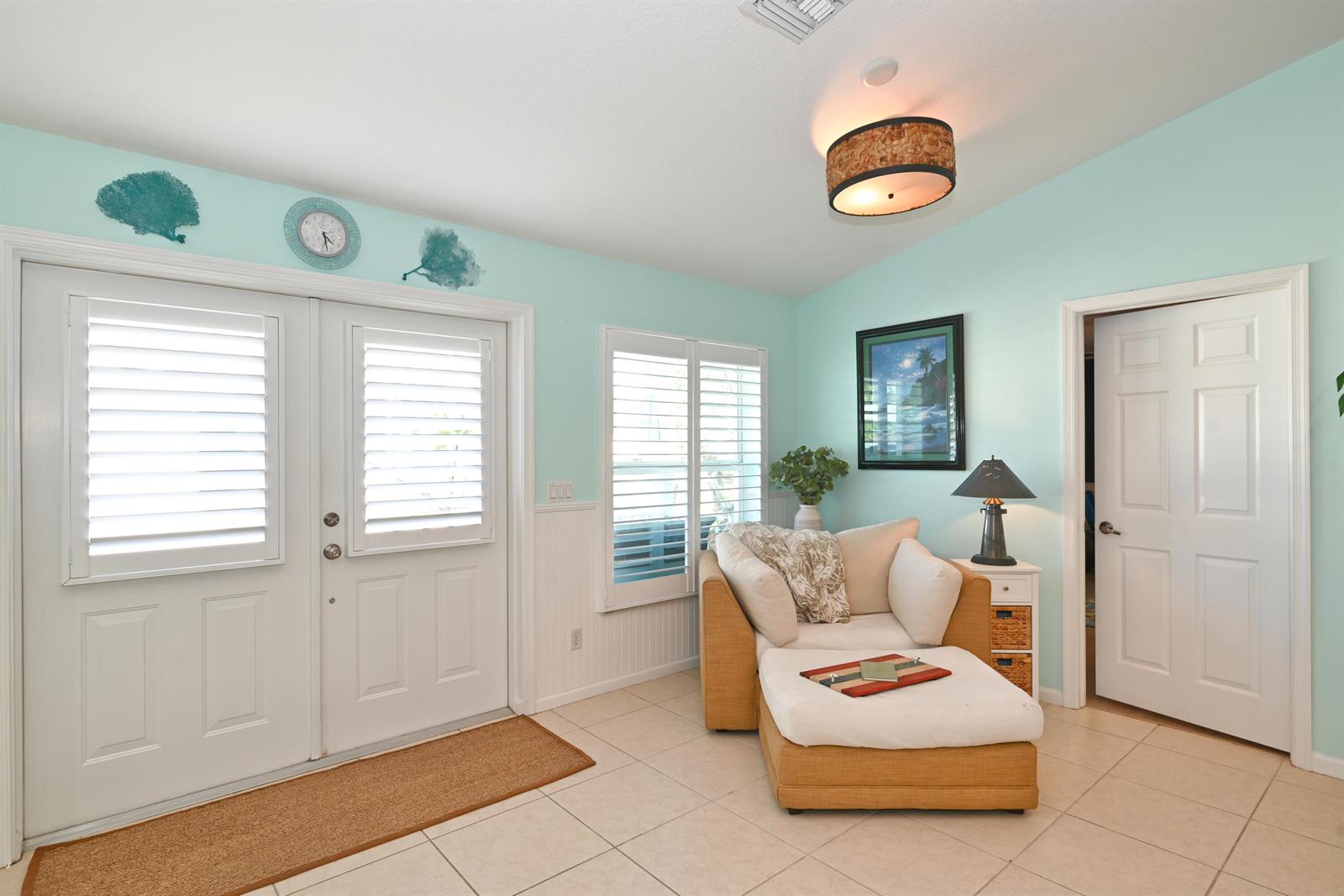 A light blue room features a tan armchair with ottoman, tiled floors, and double doors — 126 Faith Way, Jupiter FL 33458, JUPITER, FL